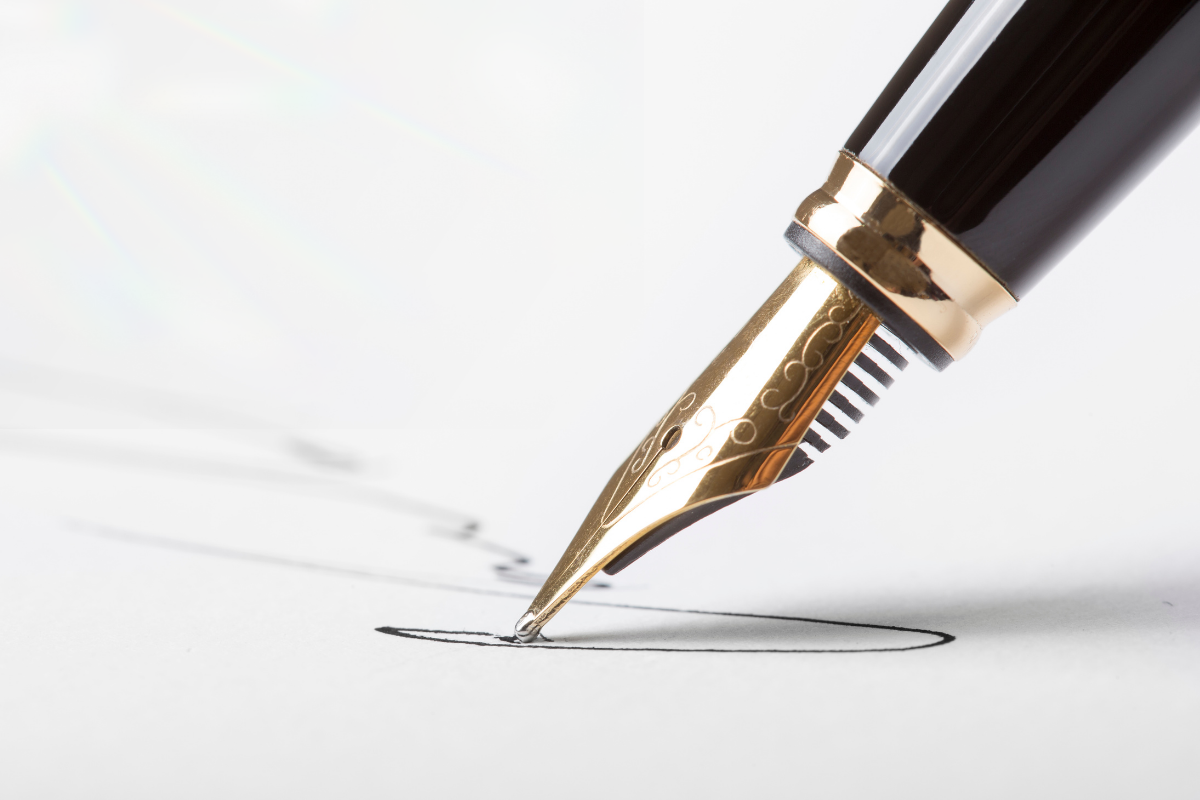 Side view of a black and gold felt pen writing on a white paper