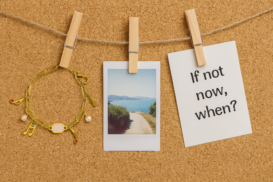 Front view of a cork board with three items hanging from it. Item one,18k gold charm bracelet, second item, a polaroid picture of a scenic road, third item, a note that says if not now, when? 